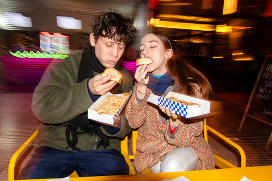 Couple eating pizza with pleasure flash portrait