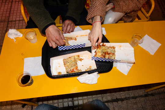 Top view of yellow table with pizza, hands reaching out