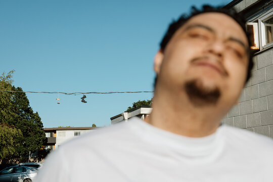 Candid portrait with hanging shoes over suburban street