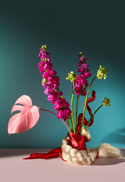 Abstract Still Life With Flowers and Blonde Braid on blue background.