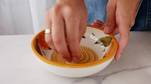 Close-up of woman grating fresh garlic on traditional Spanish ceramic grater plate for Mediterranean food preparation