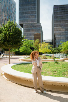 Businesswoman Talking on Mobile Phone in a Park in a Business Area