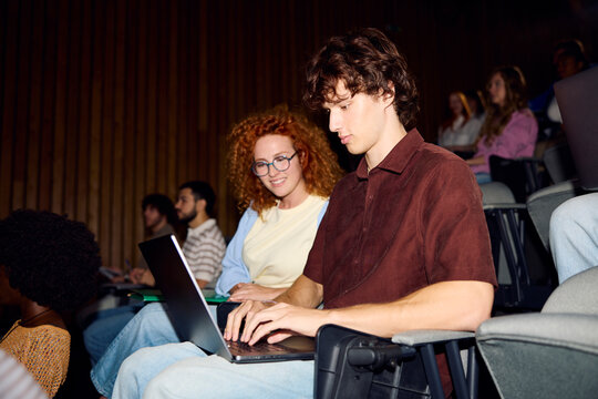 Students work together on a laptop in the auditorium