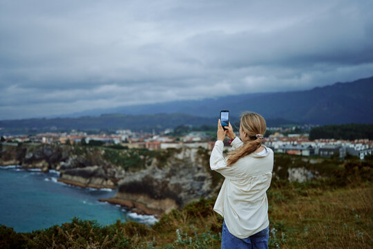 Woman Capturing Scenic View Over The Coastline
