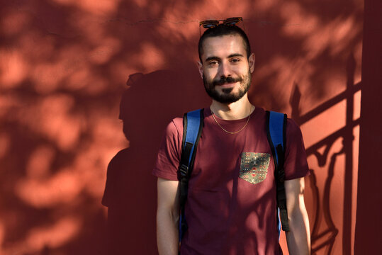 Smiling Young Traveler Standing in Warm Light Against a Red Wall