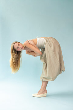 Fashion Portrait of Blonde Model Bending Forward in Cream Silk Top