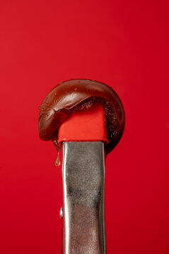 Conceptual food art: dark kumato tomato with a juice drop in tongs