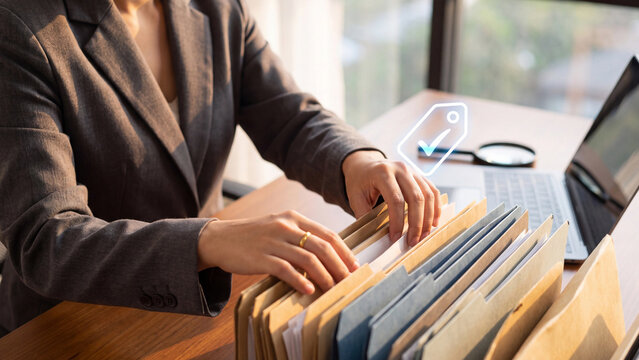File management and document organization concept, businesswoman searching folders with tag label and magnifier for paperwork archive, record keeping and office administration filing system