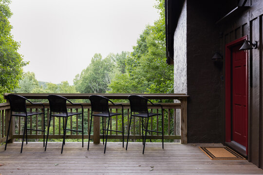 Covered Porch with Bar Stools Overlooking Green Landscape