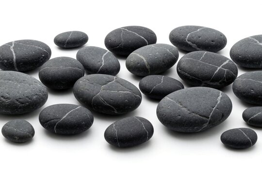 Black pebble stones with white veins arranged on white background. Various sizes, shapes of smooth dark rocks create minimal composition. Natural mineral textures for zen spa decoration, landscaping