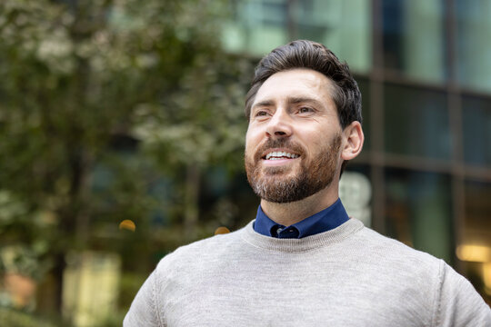 Close-up photo of a happy young man standing outside, smiling and looking ahead
