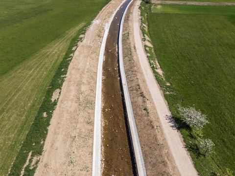 Aerial view of a river restoration project showing channel cleaning and widening for flood prevention in a rural area.