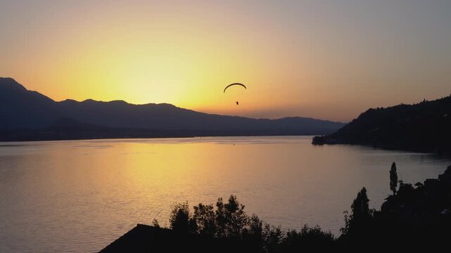 Paraglider flies over calm lake water in Thun Switzerland