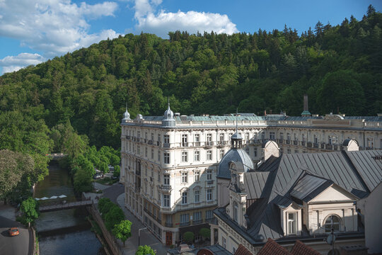 Tepla river flowing through Karlovy Vary with Hotel and forest in background in Czech Republic