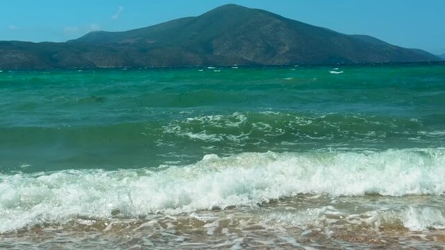 Turquoise Sea Waves Rolling Onto Sandy Beach Shore With Big Mountain Peak 