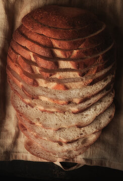 Sliced Loaf of Sourdough Bread Still life. High angle shot on a baking sheet and kitchen towel with warm side light.