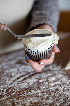 Hand frosting chocolate cupcake delicately.