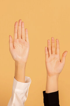 Raised hands on orange background.
