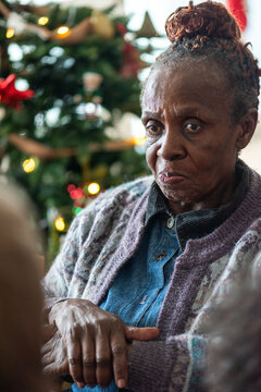 Elderly woman near Christmas tree.