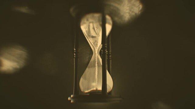 Gold sand grains running inside hourglass measuring time in countdown closeup. Falling sand showing the passing time of hourglass close-up and isolated.