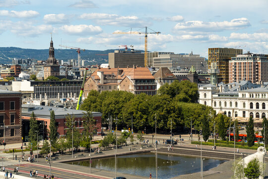 Oslo, Oslo, Norway - 23 July 2025: View of the cityscape featuring historic and modern buildings, construction cranes, a central pond, and lush green trees.