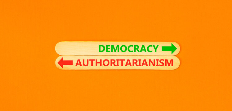 Democracy or authoritarianism words symbol. Concept words Democracy Authoritarianism on beautiful wooden sticks. Beautiful orange background. Business democracy authoritarianism concept. Copy space