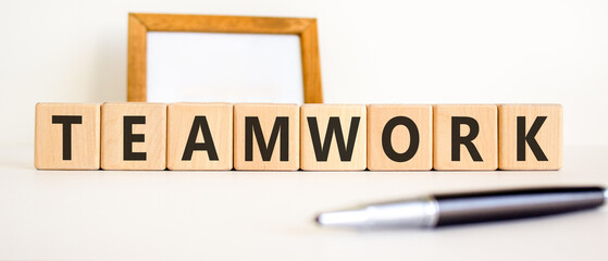 Obraz premium Teamwork word symbol. Concept word Teamwork on beautiful wooden blocks. Beautiful white background. Beautiful black pen. Business support help teamwork word concept. Copy space.