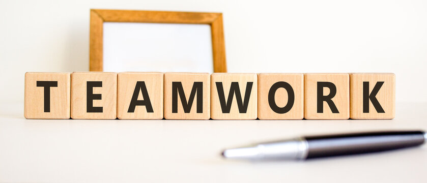 Teamwork word symbol. Concept word Teamwork on beautiful wooden blocks. Beautiful white background. Beautiful black pen. Business support help teamwork word concept. Copy space.
