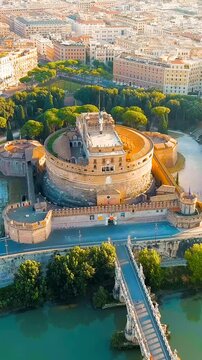 Vertical video. Rome, Italy. Castel Sant Angelo, the cylindrical Roman mausoleum turned medieval fortress, Drone footage at morning light over the Tiber River with its fortified bastions and historic