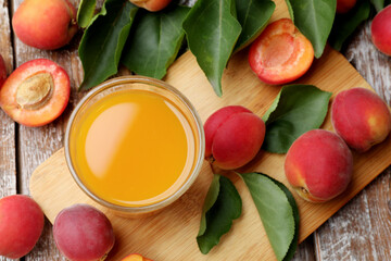 Apricot juice in glass, fresh fruits and leaves on wooden table, flat lay © New Africa