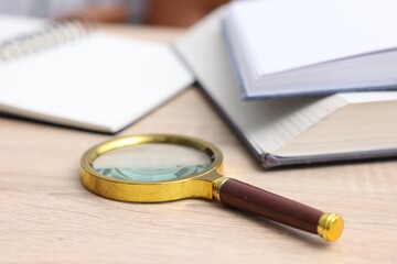 Fototapeta premium Keywords. Magnifying glass, books and notebook on wooden table, selective focus
