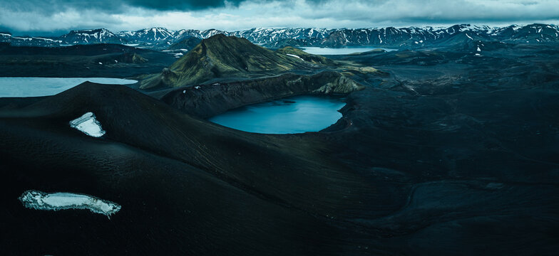 Panoramic view of Lj&oacute;tipollur crater lake in Iceland's Highlands, surrounded by dark volcanic slopes beneath dramatic storm clouds. A remote and breathtaking volcanic landscape.
