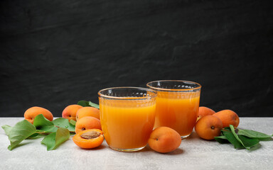 Apricot juice in glasses, fresh fruits and leaves on light table, closeup © New Africa