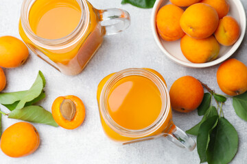 Apricot juice in mason jars, fresh fruits and leaves on light table, flat lay © New Africa