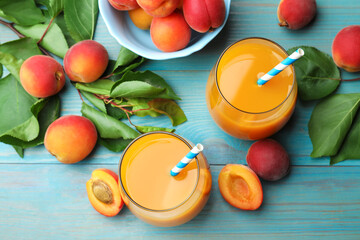 Apricot juice in glasses, fresh fruits and leaves on light blue wooden table, above view © New Africa