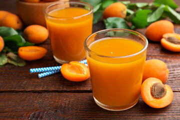 Apricot juice in glasses, fresh fruits and drinking straws on wooden table, closeup © New Africa