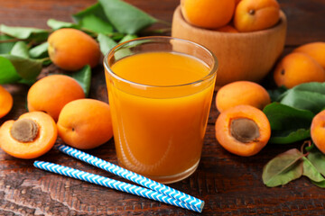 Apricot juice in glass, fresh fruits and drinking straws on wooden table, closeup © New Africa