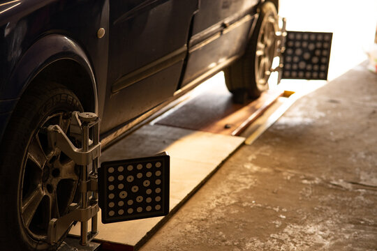 Car wheel alignment target clamps mounted on tires in garage.