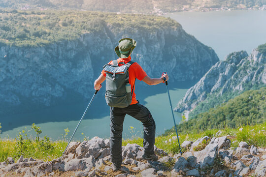 Man standing on mountain peak, looking at a winding Danube river below a deep Iron Gates canyon, enjoying nature and outdoor adventure