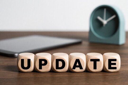 Wooden dice blocks spell word update on desk. Smartphone, clock in background on office table. Concept of software upgrade, system renewal data processing in modern workspace. Business technology