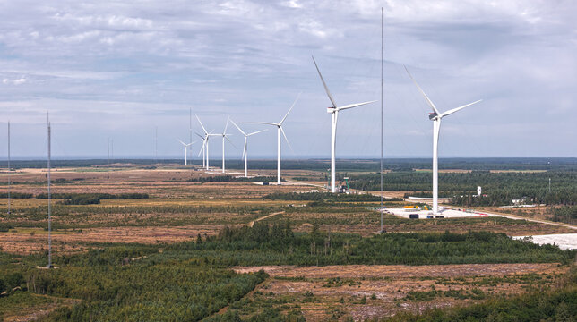Aerial view of the Wind Turbine Test Center Osterild featuring a row of large offshore wind turbines and tall measuring masts set against a vast landscape in Osterild, Denmark.