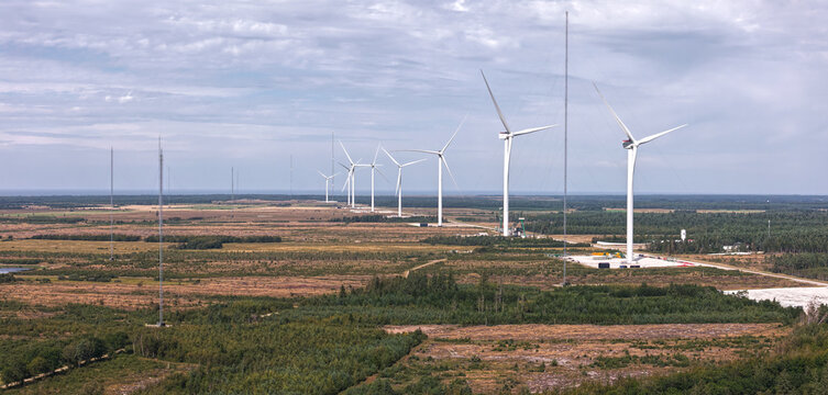 Aerial view of the Wind Turbine Test Center Oesterild featuring large offshore wind turbines and tall measuring masts set against a vast landscape in Osterild, Denmark.