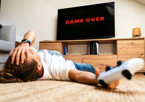 Disappointed female gamer after losing a video game with &ldquo;Game Over&rdquo; displayed on TV