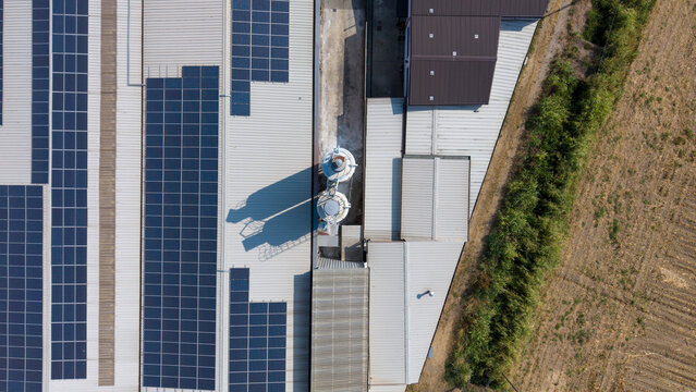 Aerial view of a specialty coatings manufacturing facility featuring extensive rooftop solar panels and industrial silos adjacent to a field in Milan, Lombardy, Italy.