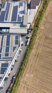 Aerial view of a specialty coatings manufacturing facility featuring extensive rooftop solar panels, adjacent to a field in Milan, Lombardy, Italy.