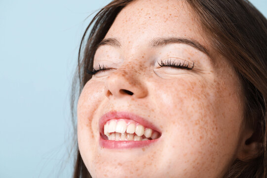 Beautiful teenage girl with freckles on light blue background, closeup. Space for text