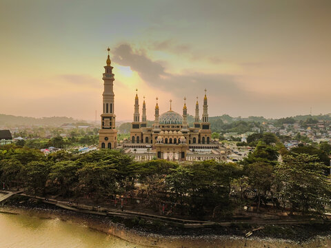 Aerial view of Baitul Muttaqien Mosque, also known as the East Kalimantan Islamic Center, featuring its prominent dome and minarets set against a sunset sky in Samarinda, East Kalimantan, Indonesia.