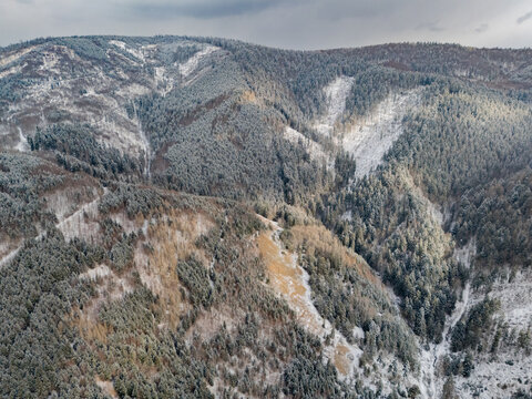Aerial view of the old copper mine dumps in Svatodusna dolina surrounded by snow-dusted pine forests and rugged mountain terrain in Lubietova, Banska Bystrica Region, Slovakia.