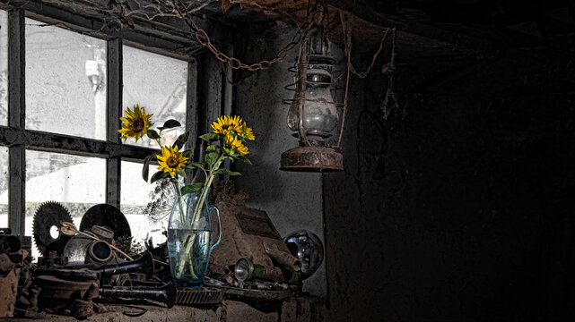 A romantic setting in a creative studio. A beautiful bouquet of sunflowers on the window. Objects and tools scattered haphazardly in the garage. A lively still life, impromptu. Yellow filling light.