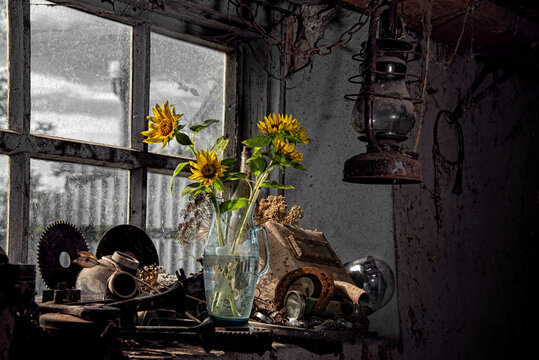 A romantic setting in a creative studio. A beautiful bouquet of sunflowers on the window. Objects and tools scattered haphazardly in the garage. A lively still life, impromptu. Yellow filling light.